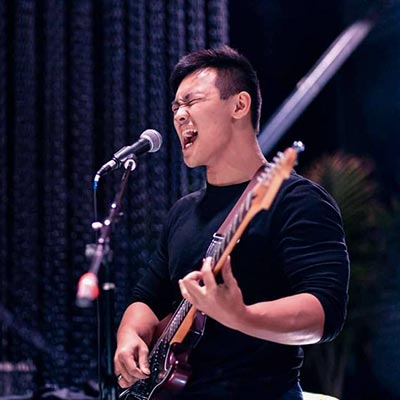 rock guitarist plays and sings into microphone on stage