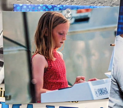 Young girl plays piano keyboard at farmer's market recital